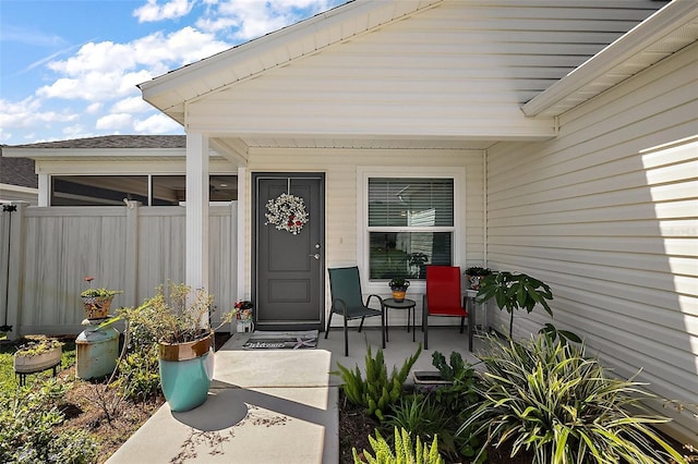 entrance to property with covered porch and fence
