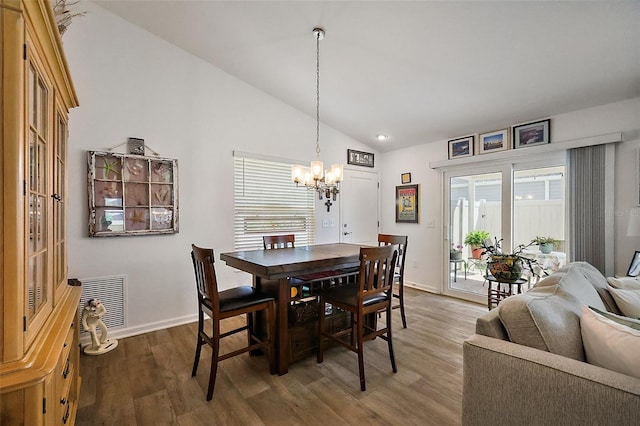 dining area featuring lofted ceiling, baseboards, wood finished floors, and a chandelier
