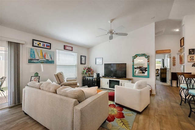 living room featuring vaulted ceiling, wood finished floors, baseboards, and ceiling fan