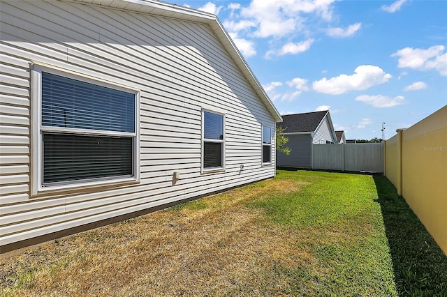 view of side of home with fence and a yard