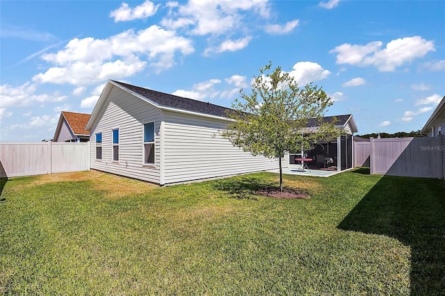 view of side of property featuring a lawn, a fenced backyard, and a patio