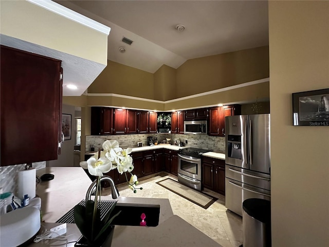 3511 Fox Lake Dr, Apopka, FL 32712 - kitchen with stainless steel appliances, light countertops, lofted ceiling, backsplash, and reddish brown cabinets