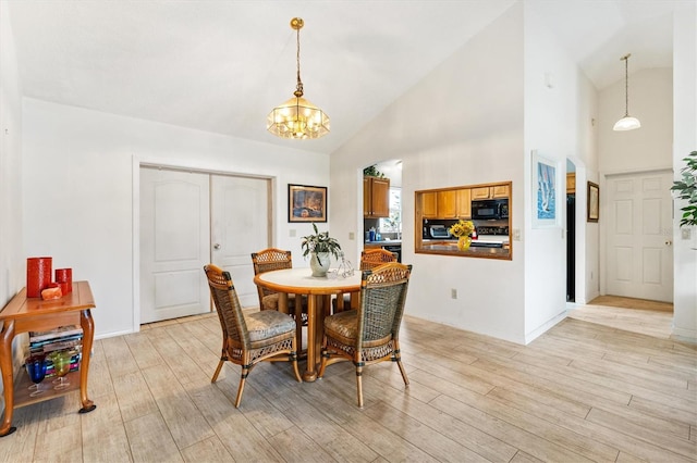 dining area featuring a chandelier, light wood finished floors, and high vaulted ceiling