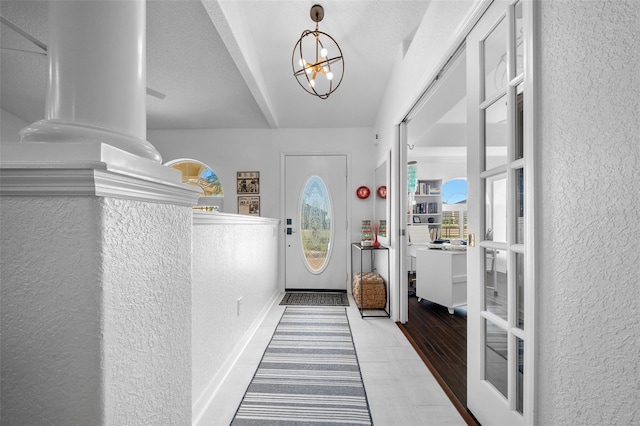 entrance foyer featuring a textured wall, baseboards, and an inviting chandelier