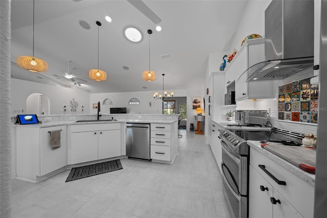 kitchen with ceiling fan with notable chandelier, wall chimney range hood, appliances with stainless steel finishes, a sink, and lofted ceiling