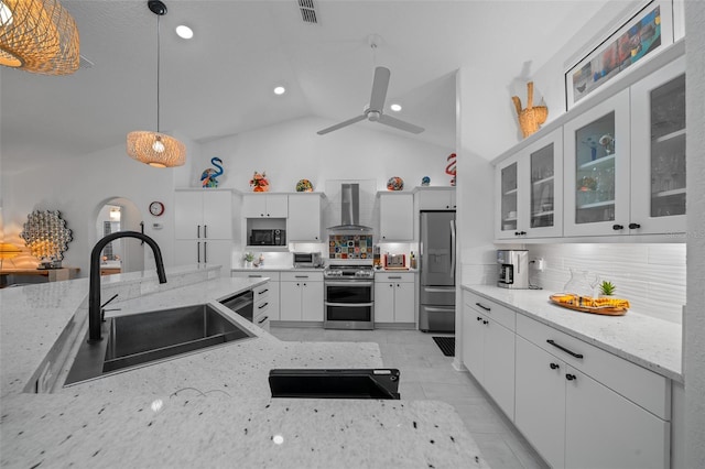 kitchen featuring visible vents, wall chimney exhaust hood, a sink, appliances with stainless steel finishes, and pendant lighting