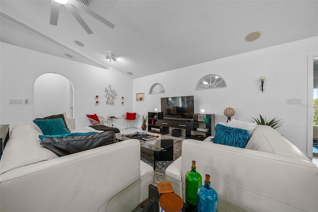 living area with arched walkways, ceiling fan, and lofted ceiling