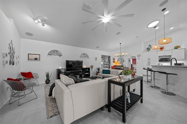 living area with baseboards, a textured ceiling, visible vents, high vaulted ceiling, and ceiling fan with notable chandelier