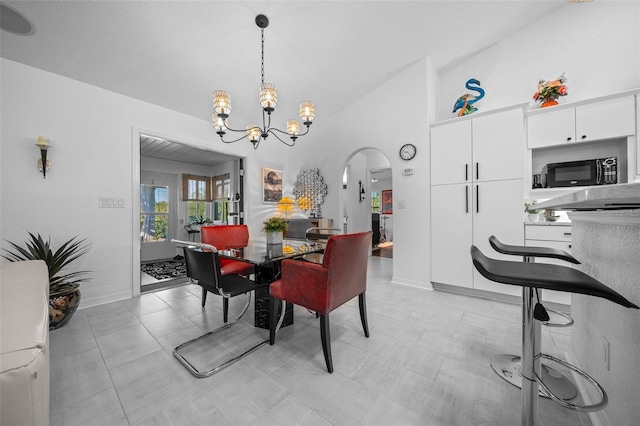 dining space featuring baseboards, high vaulted ceiling, arched walkways, and a chandelier