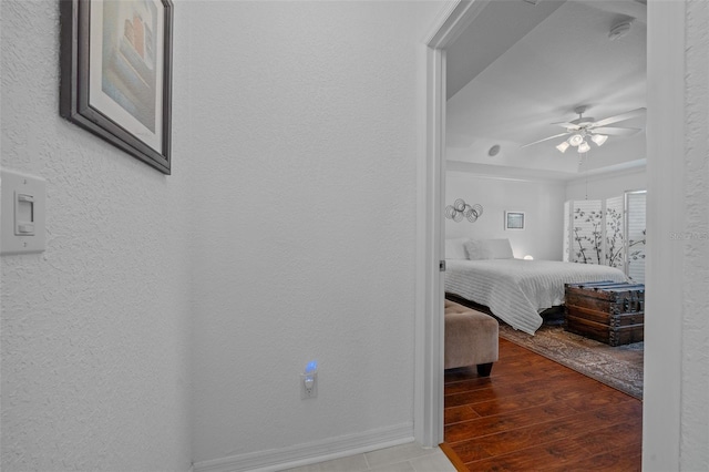 bedroom with wood finished floors, a textured wall, and ceiling fan