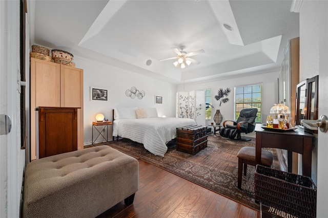 bedroom with a ceiling fan, a raised ceiling, and wood-type flooring