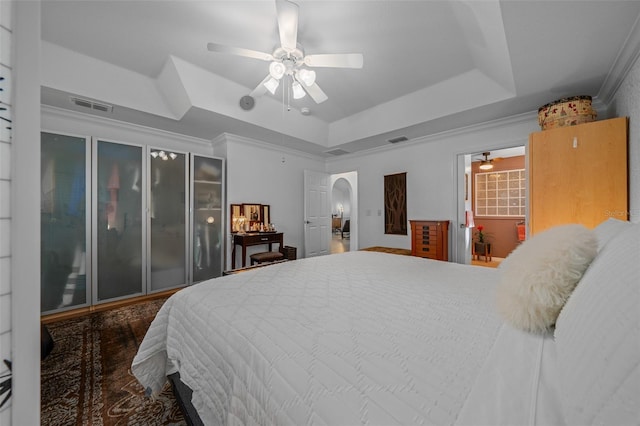 bedroom featuring visible vents, ceiling fan, a tray ceiling, and arched walkways