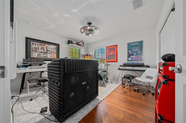 office with visible vents, a textured ceiling, and wood finished floors