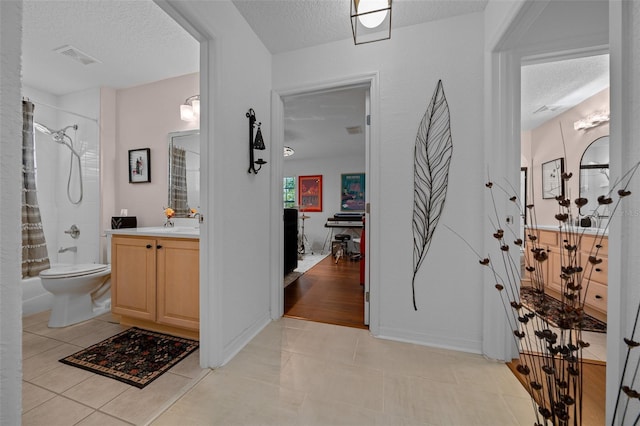 full bath with a textured ceiling, vanity, tile patterned flooring, toilet, and shower / tub combo with curtain