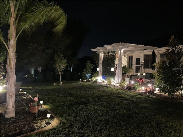 yard at night featuring a pergola