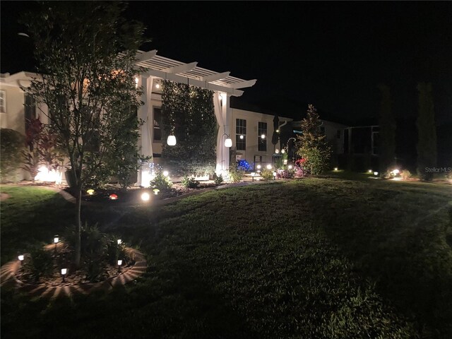 yard at night featuring a pergola