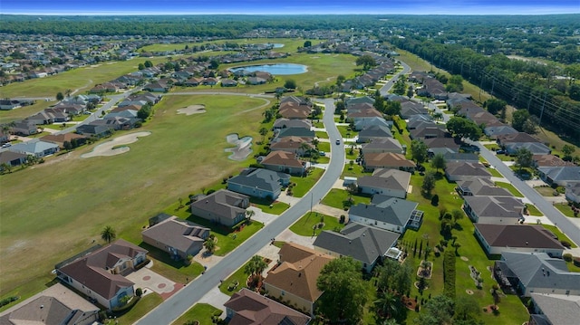 drone / aerial view with view of golf course, a residential view, and a water view