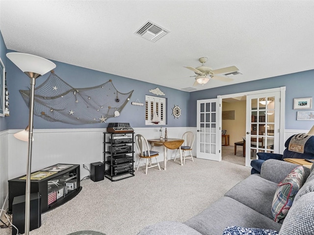 1307 Galindo Pl, The Villages, FL 32159 - carpeted living room featuring a textured ceiling, a ceiling fan, visible vents, wainscoting, and french doors