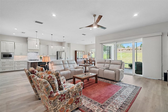 living area with recessed lighting, a textured ceiling, a ceiling fan, light wood-style floors, and visible vents