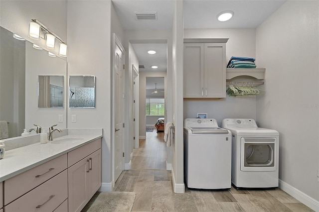 washroom with independent washer and dryer, a sink, visible vents, and wood tiled floor