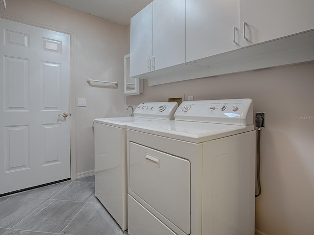 clothes washing area with light tile patterned floors, baseboards, cabinet space, and independent washer and dryer