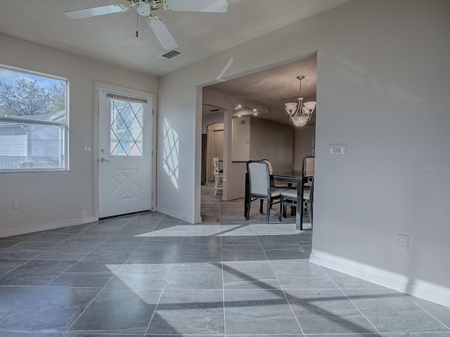 entryway with baseboards, a textured ceiling, visible vents, and ceiling fan with notable chandelier