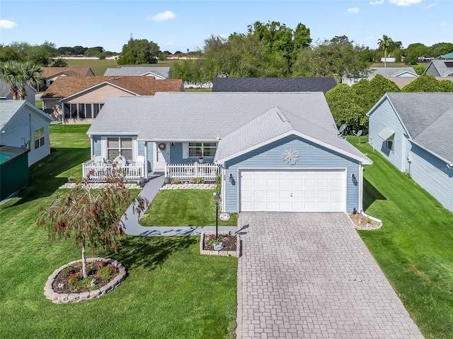 ranch-style home featuring a residential view, decorative driveway, a front lawn, an attached garage, and a porch