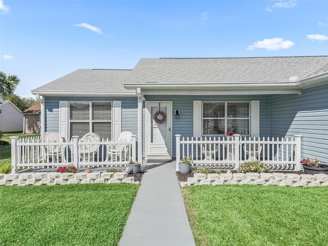 view of front facade with a porch, a shingled roof, and a front yard