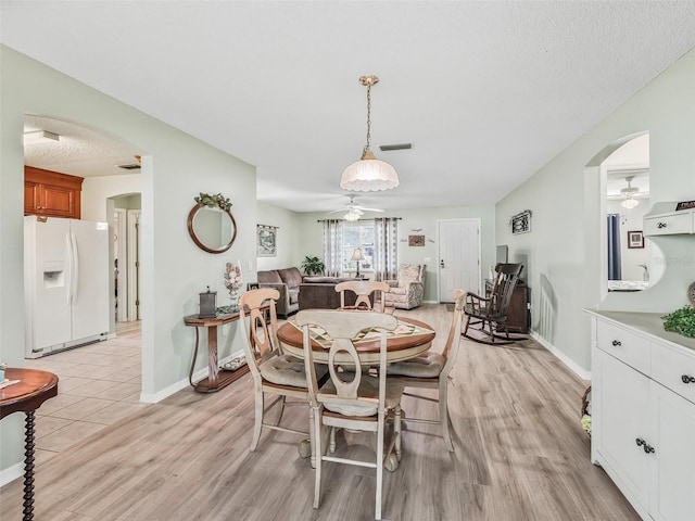 dining room featuring visible vents, ceiling fan, arched walkways, and light wood-style floors