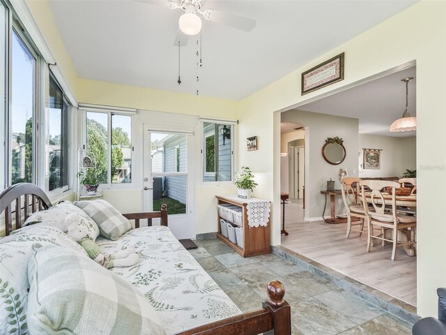 bedroom featuring arched walkways, baseboards, a ceiling fan, and stone finish flooring