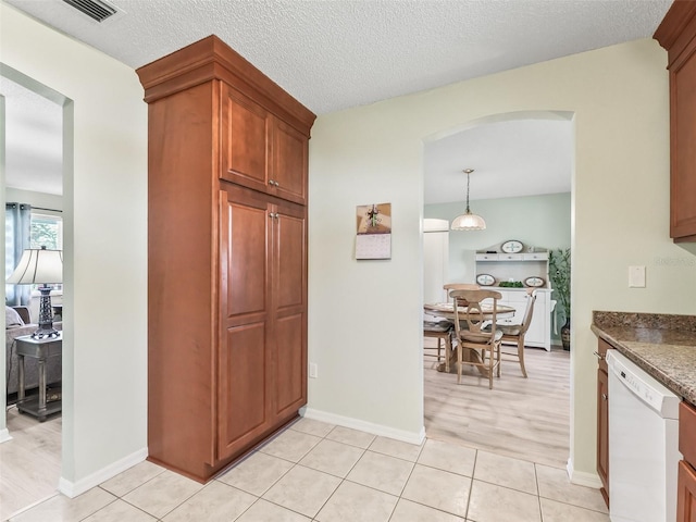 kitchen with white dishwasher, visible vents, a textured ceiling, and light tile patterned floors