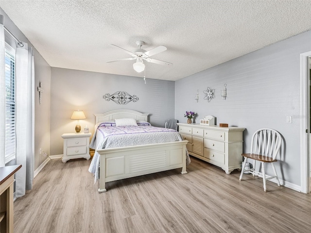 bedroom with a textured ceiling, light wood finished floors, baseboards, and a ceiling fan