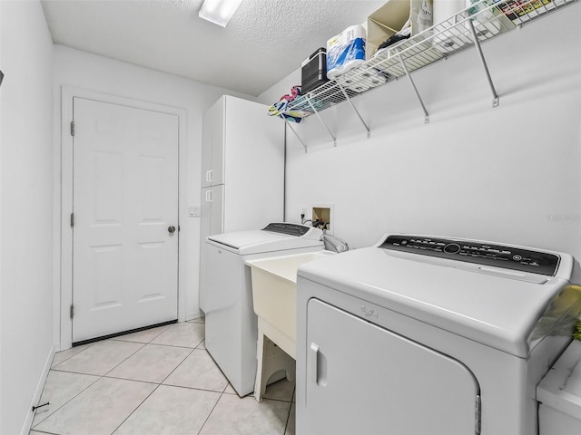 laundry area with light tile patterned floors, washing machine and dryer, laundry area, and a textured ceiling
