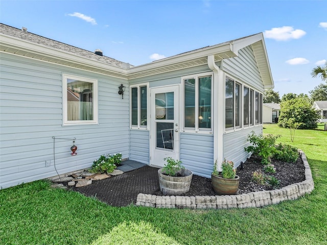 view of side of property with a sunroom and a lawn