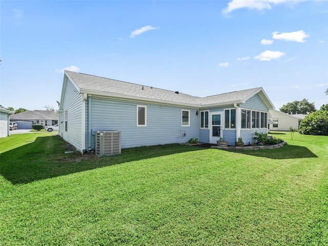 back of house featuring a sunroom, a shingled roof, central AC unit, and a lawn