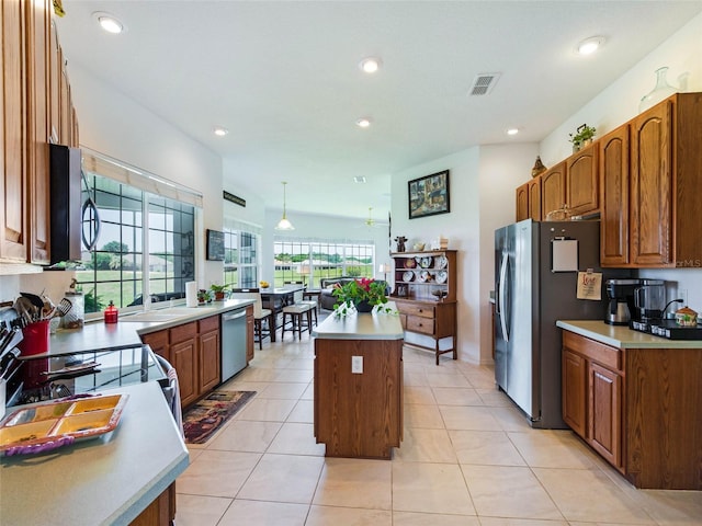 kitchen featuring brown cabinets, a kitchen island, visible vents, and stainless steel appliances
