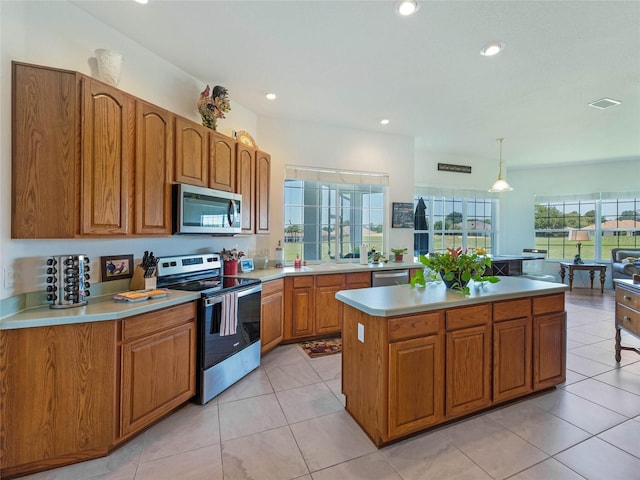 kitchen with brown cabinets, appliances with stainless steel finishes, light countertops, and a kitchen island