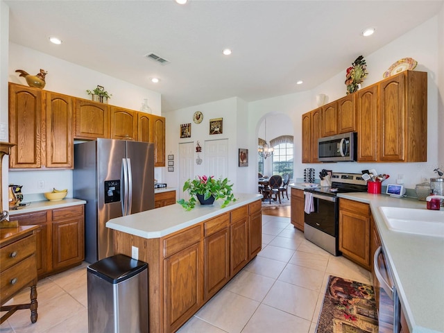 kitchen featuring a center island, visible vents, appliances with stainless steel finishes, arched walkways, and a sink