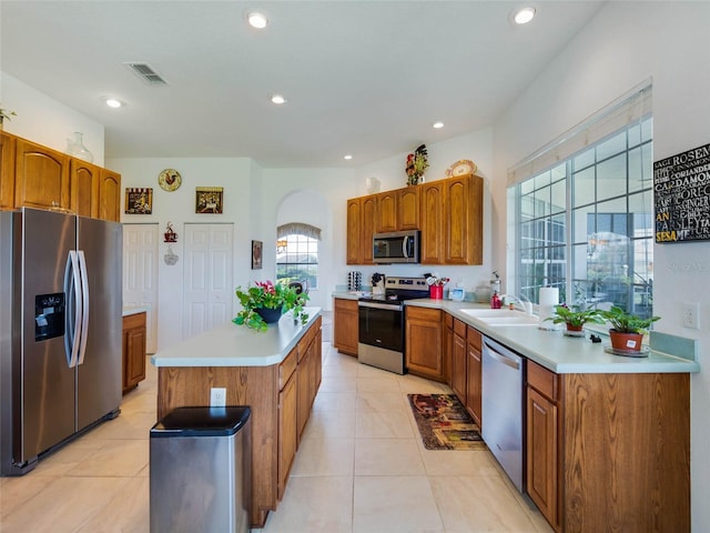 kitchen with light tile patterned floors, visible vents, a center island, stainless steel appliances, and brown cabinets