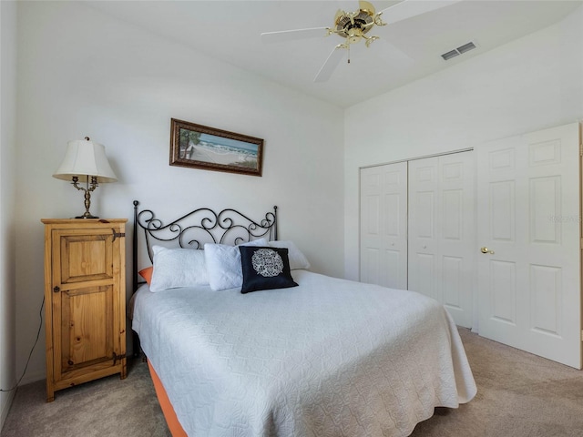 bedroom with visible vents, a ceiling fan, a closet, and light colored carpet