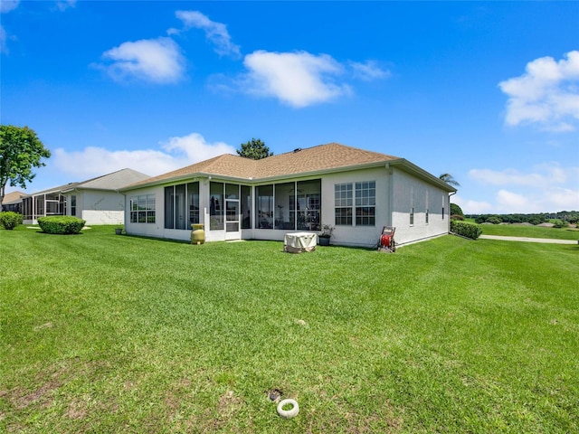 back of house featuring stucco siding, a sunroom, and a lawn