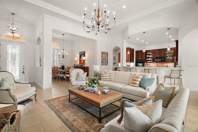 living room featuring arched walkways, ornamental molding, a chandelier, light tile patterned flooring, and baseboards