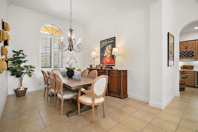 dining area featuring light tile patterned floors, baseboards, arched walkways, a notable chandelier, and ornamental molding
