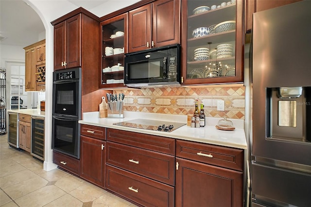 kitchen featuring arched walkways, light countertops, black appliances, backsplash, and beverage cooler