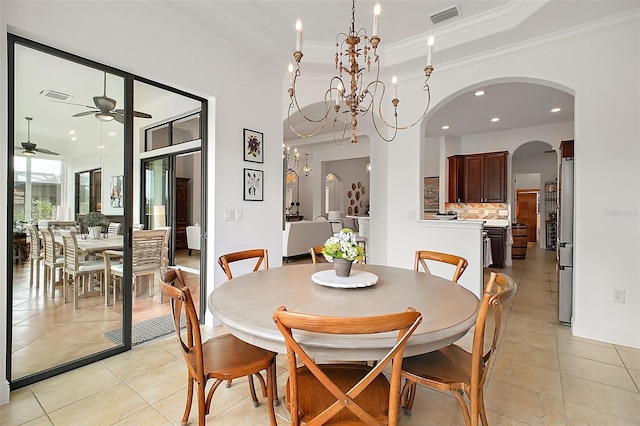 dining space with a tray ceiling, crown molding, ceiling fan with notable chandelier, and visible vents