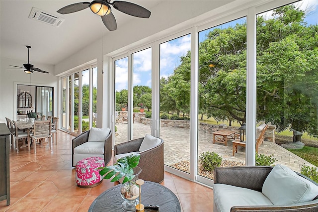 sunroom featuring outdoor dining space, tile patterned flooring, visible vents, and a ceiling fan