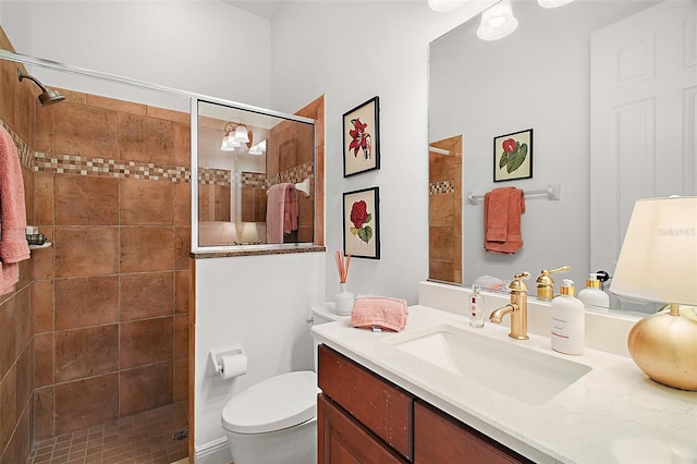 full bath with vanity, a tile shower, and toilet