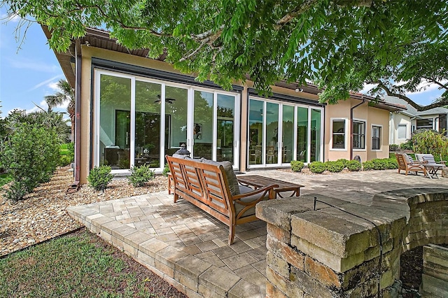 rear view of property featuring a patio area, stucco siding, and a sunroom