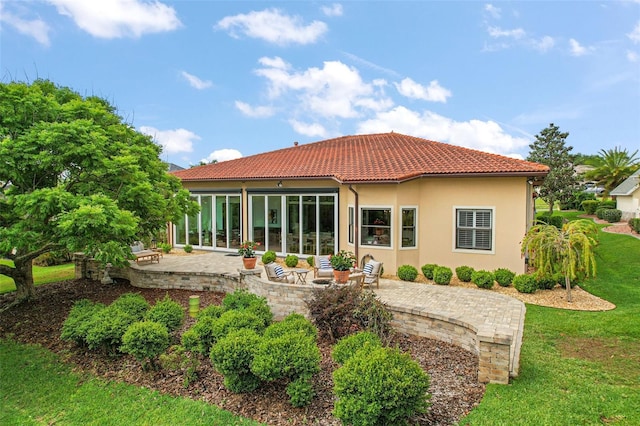 rear view of property with a patio, a yard, stucco siding, and a tile roof