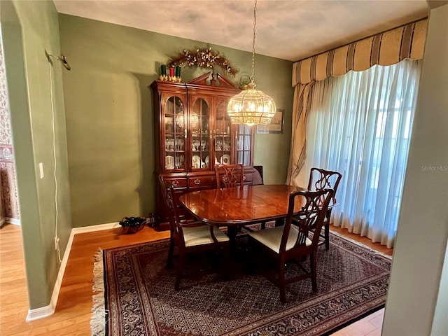 dining area with a chandelier, light wood-style flooring, and baseboards
